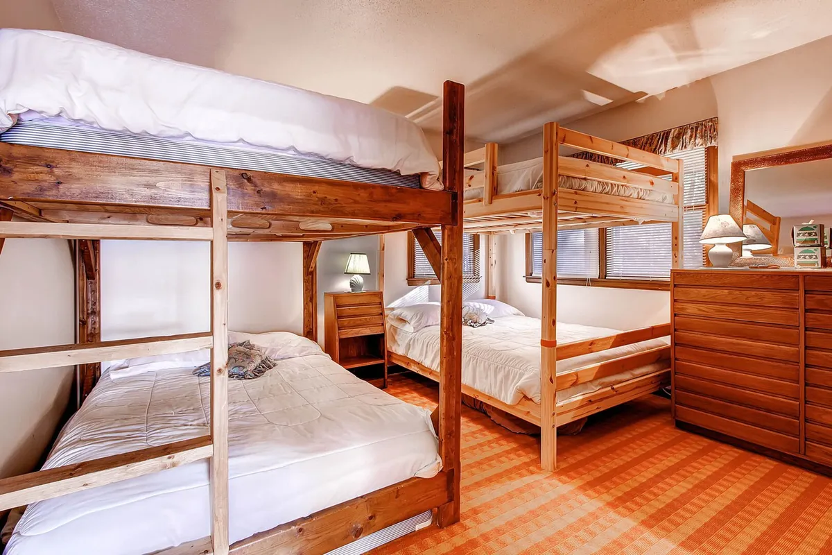 A bright and communal bedroom featuring bunk beds, a double bed, and ample storage with a dresser and dressing table. The space feels friendly and inviting, perfect for group activities, bedtime stories, and multi-generational stays.