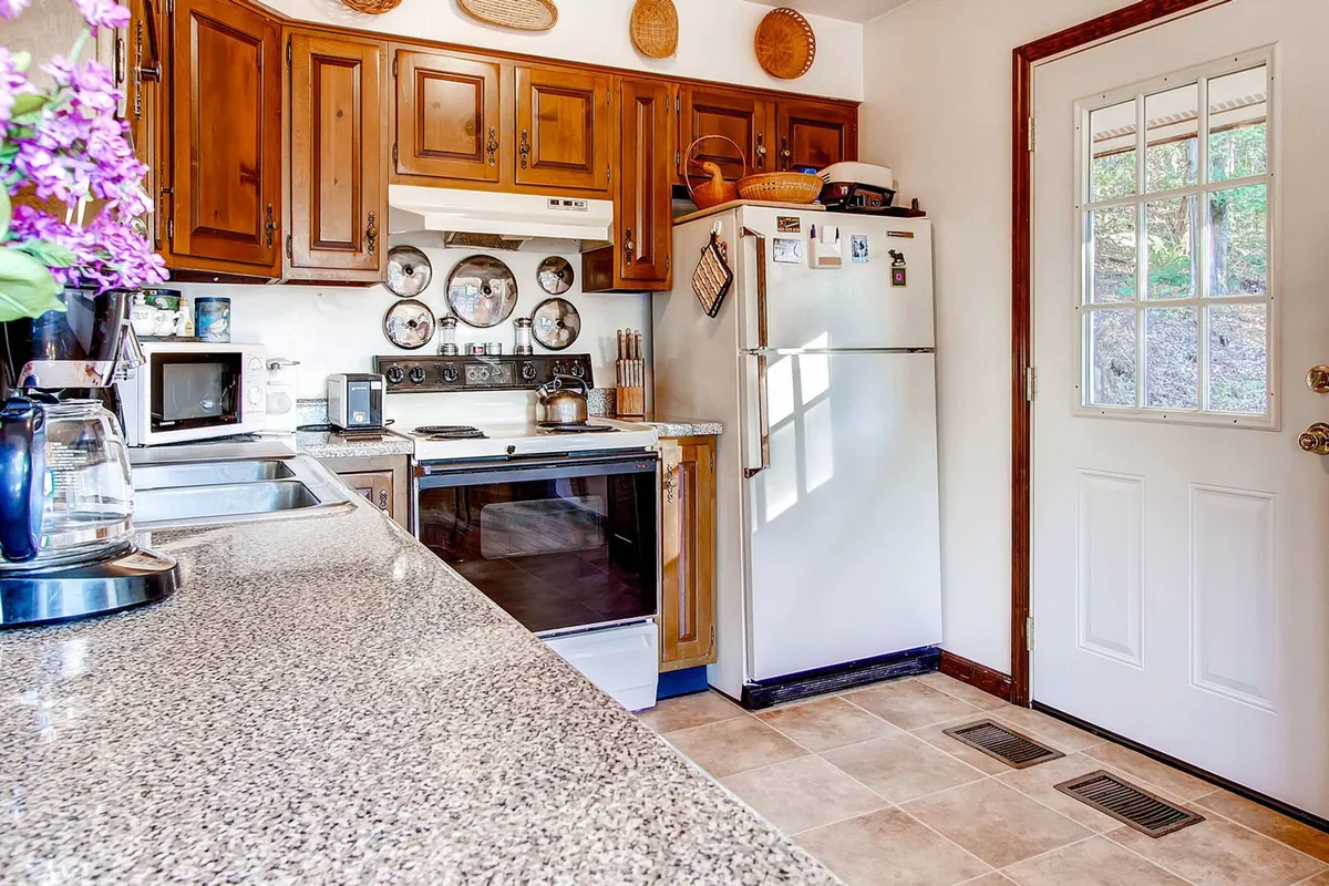 A functional kitchen area with ample countertop space, modern appliances, and a visible door leading to another part of the house—possibly near an entryway or mudroom. The setting is designed for convenience and gathering, supporting both meal prep and gear drop-off.