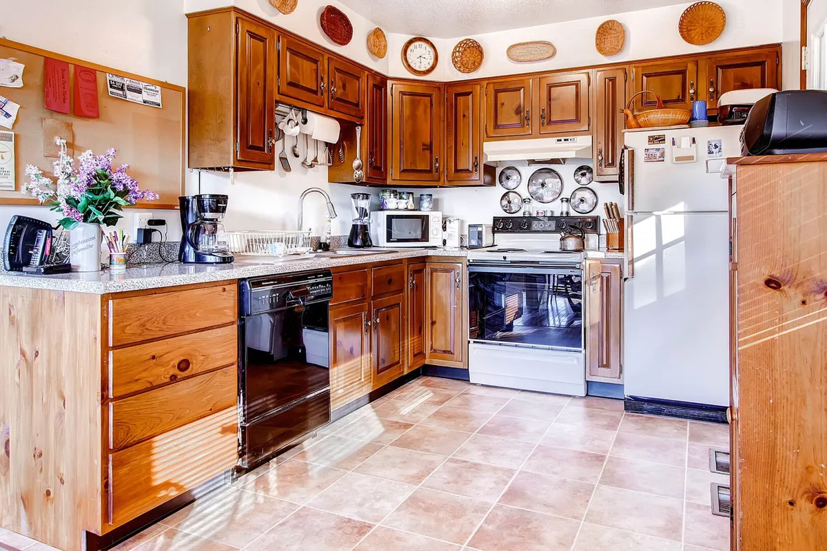 A fully equipped kitchen with a spacious counter, gleaming stainless steel appliances, and wooden cabinetry, all arranged for both cooking and socializing. Decorative plates and homey touches enhance the atmosphere, making it ideal for preparing meals together.
