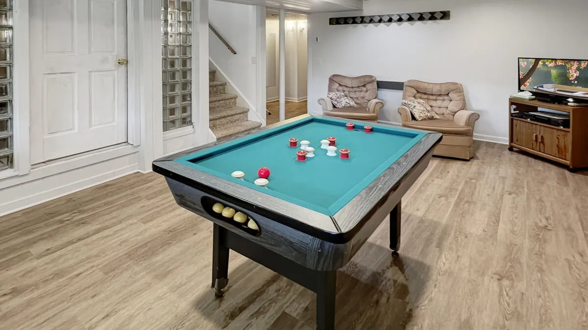 A lively game room featuring a bumper pool table, comfortable seating, and a large television. The atmosphere is casual and relaxed, ideal for friendly competition or family movie nights—welcoming for guests of all ages.